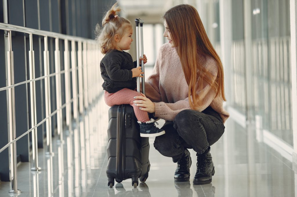 kid sitting on a suitcase in an airport